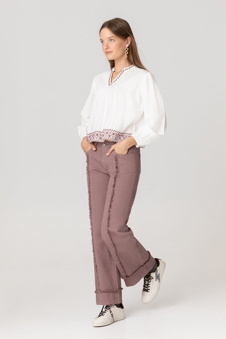 Calças de ganga com costuras desfiadas e bainha dobrada.