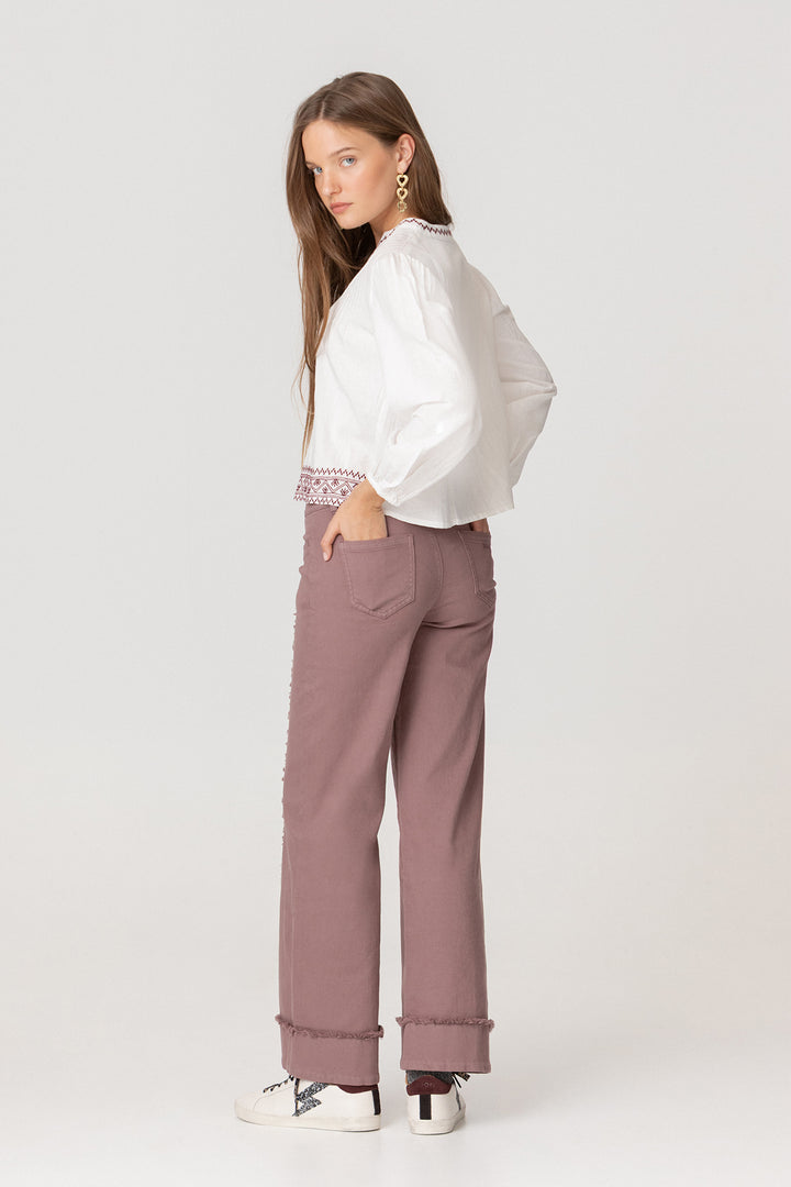 Calças de ganga com costuras desfiadas e bainha dobrada.