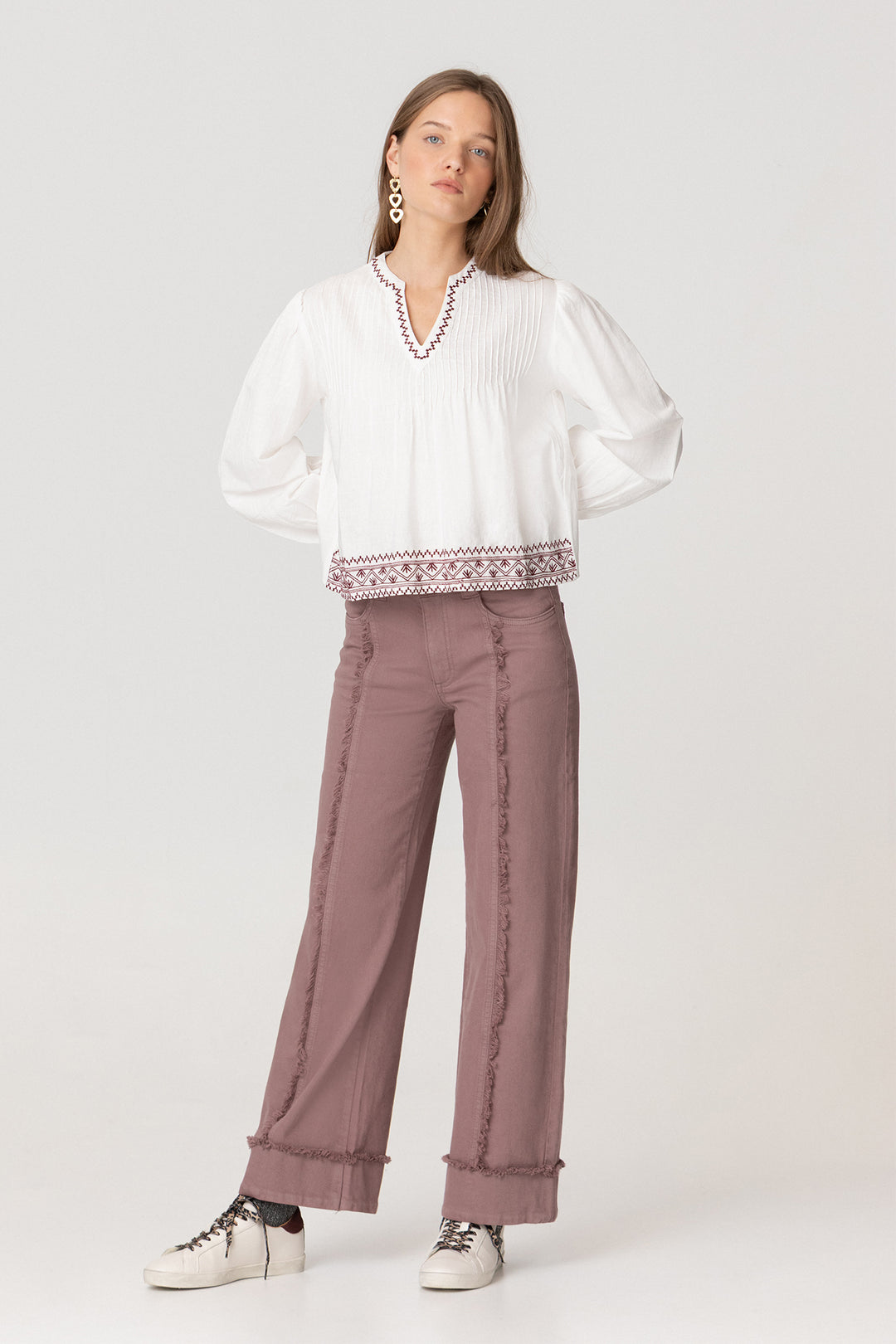 Calças de ganga com costuras desfiadas e bainha dobrada.