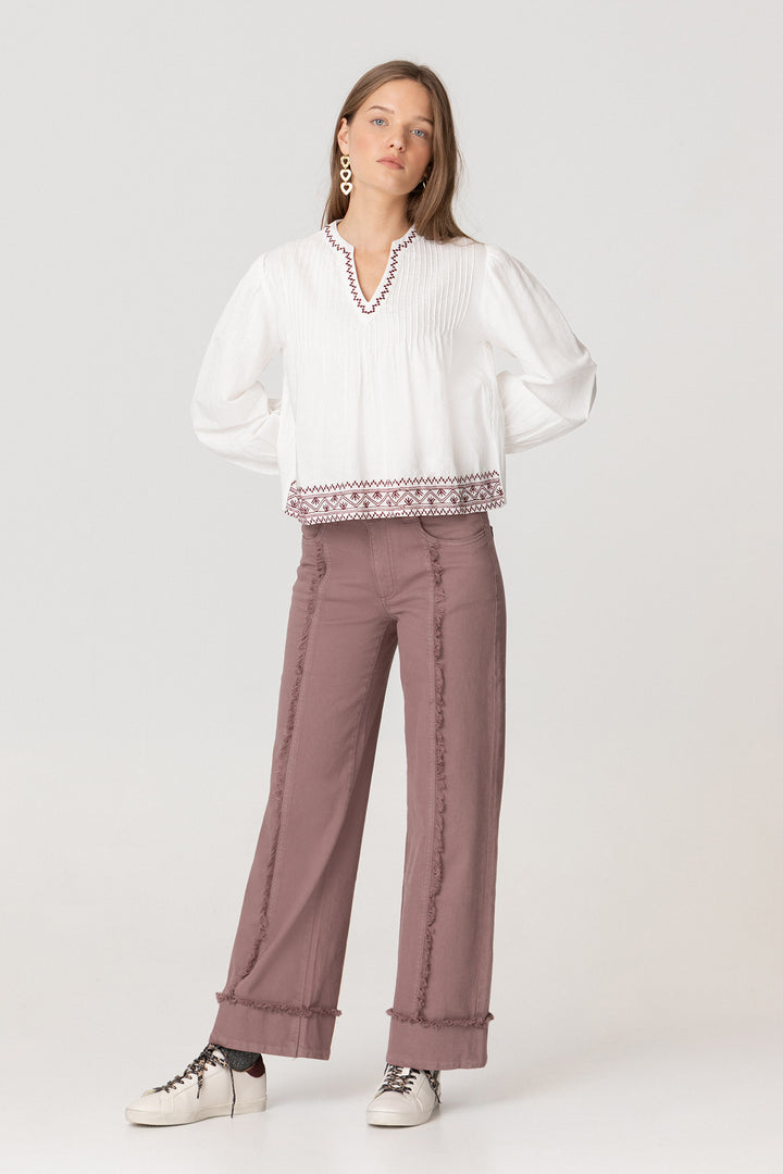 Calças de ganga com costuras desfiadas e bainha dobrada.